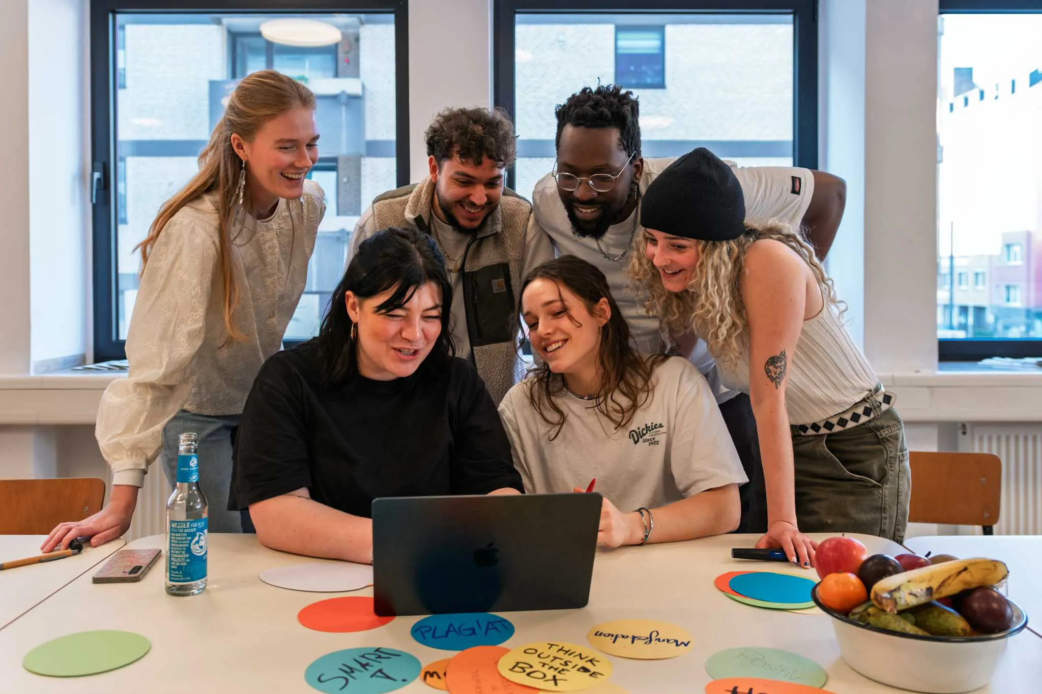 Sechs Personen schauen gemeinsam in ein Laptop